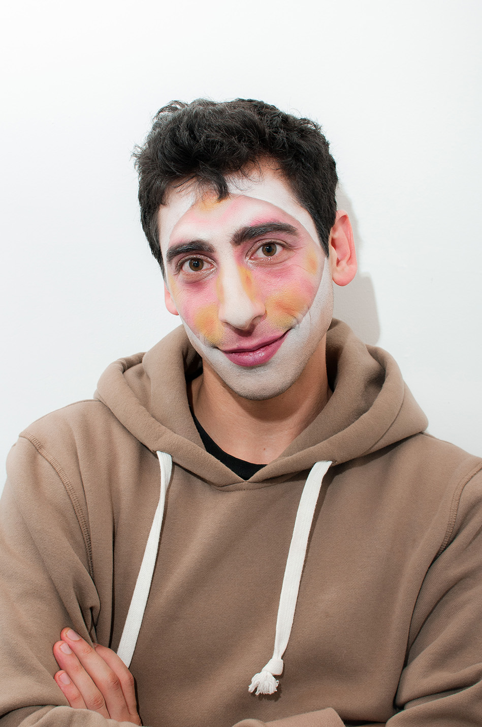 Man with diamond facepaint in various warm tones smiles at the camera